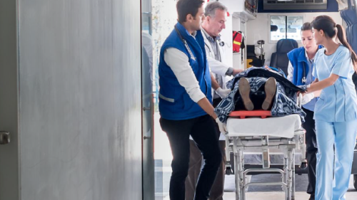 Paciente siendo trasladado en camilla desde una ambulancia al interior de un edificio